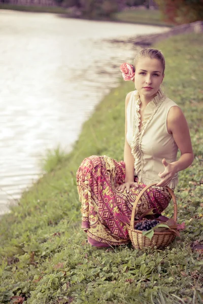 Beautiful girl in a long skirt with a basket of grapes — Stock Photo, Image