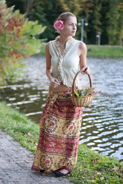 Mooi meisje in een lange rok met een mandje van druiven — Stockfoto