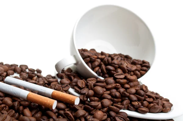 Taza llena con granos de café y cigarrillos — Foto de Stock