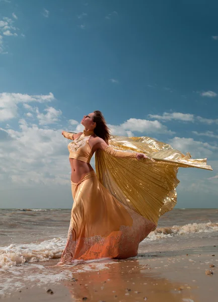Mulher de vestido exótico em pé na praia — Fotografia de Stock