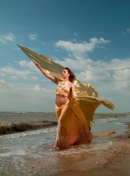 Женщина в экзотическом платье стоит на пляже — стоковое фото