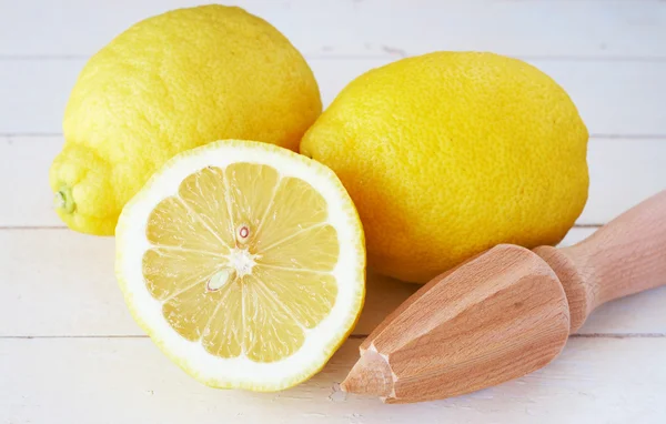 Primer plano de tres limones y exprimidor de limón en blanco Imágenes de stock libres de derechos