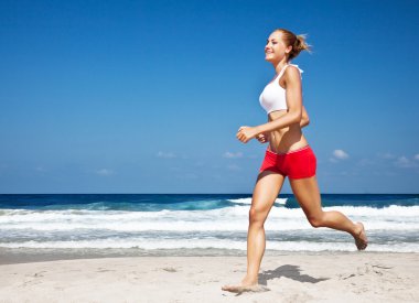 Healthy woman running on the beach clipart