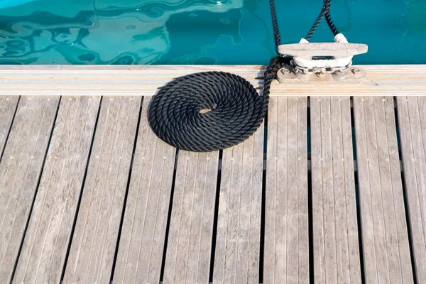 Mooring wooden pier with coiled spiral rope and a bitt — Stock Photo, Image