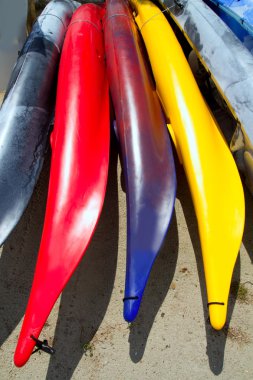 Beach colorful kayak rows lying on sand in sunny day clipart