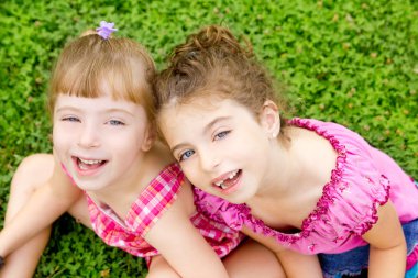 Children girls laughing sit on green grass clipart