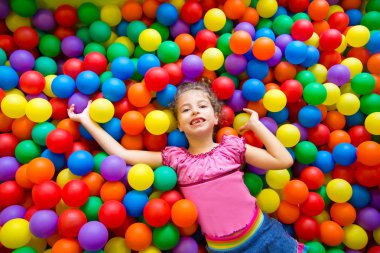 Child girl on colorful balls playground high view clipart