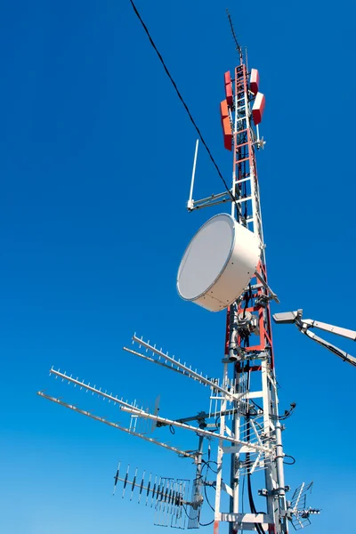 Repetidor de antena mastro bagunçado no céu azul — Fotografia de Stock
