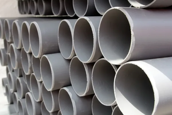 Tubes PVC gris tuyaux en plastique empilés en rangées — Photo