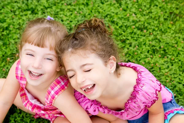 Nevetve gyerekek lányok ülnek, a zöld fű — Stock Fotó