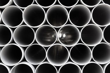 Gray PVC tubes plastic pipes stacked in rows clipart