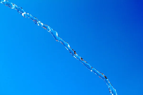 Water splash op blauwe hemelachtergrond — Stockfoto