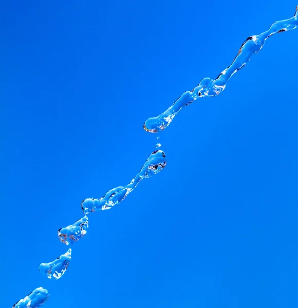 Water splash op blauwe hemelachtergrond — Stockfoto