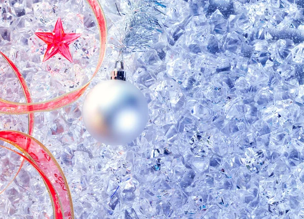Рождественская серебряная безделушка и красная лента на льду — стоковое фото