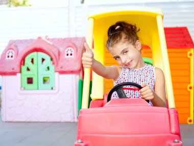 Children girl driving a toy car with ok gesture clipart