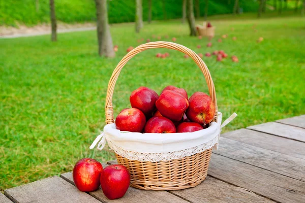 Cesta de maçãs vermelhas no chão de madeira — Fotografia de Stock
