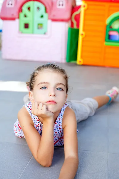 Красива маленька серйозна дівчинка лежить на підлозі — стокове фото