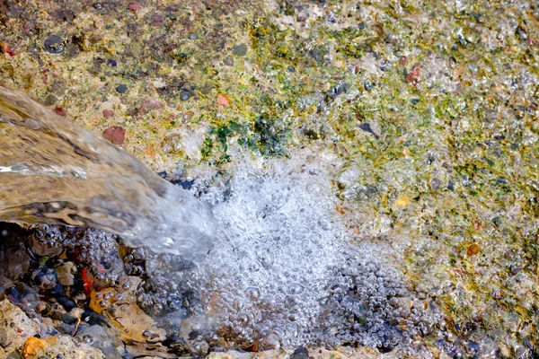 Падение воды в маленьком водопаде в источнике воды — стоковое фото