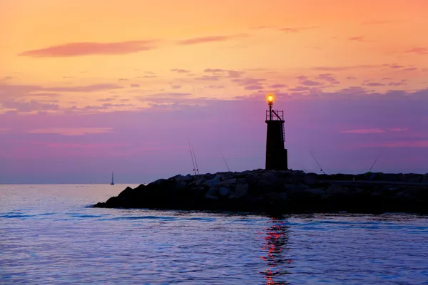 Sunrise lighthouse glowing in blue purple sea — Stock Photo, Image