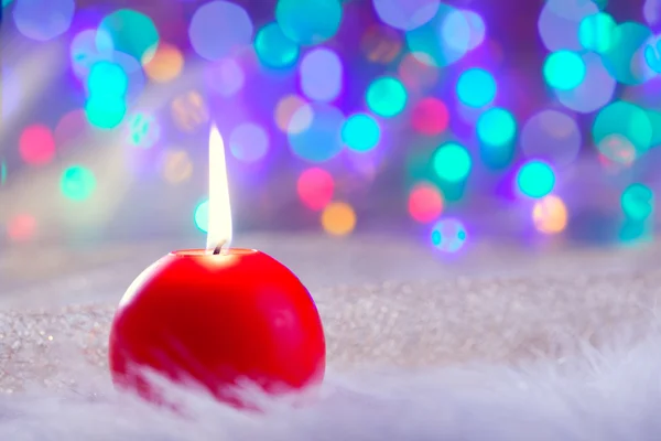 Χριστούγεννα κόκκινο κερί επί των γουνών και πολύχρωμο φως — Φωτογραφία Αρχείου