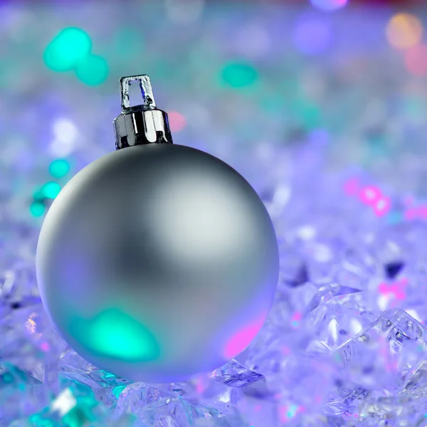 Christmas silver bauble on colorful glowing ice — Stock Photo, Image