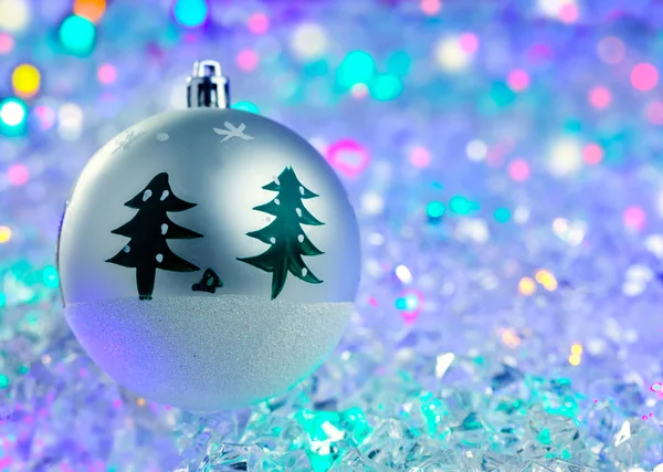 Christmas silver bauble on colorful glowing ice — Stock Photo, Image