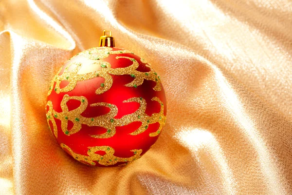 Christmas red bauble on golden fabric — Stock Photo, Image
