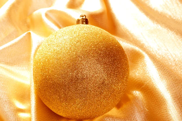 Christmas gold glitter bauble on golden fabric — Stock Photo, Image