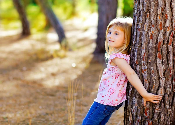 Menina criança loira no tronco da árvore de outono — Fotografia de Stock