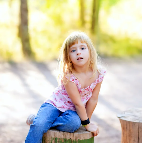 Blond kid girl in tree trunk forest — Stock Photo, Image
