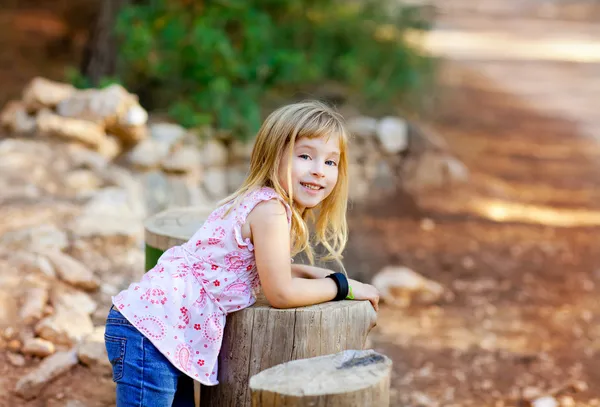 Blond dziecko dziewczynka w lesie pnia drzewa — Zdjęcie stockowe