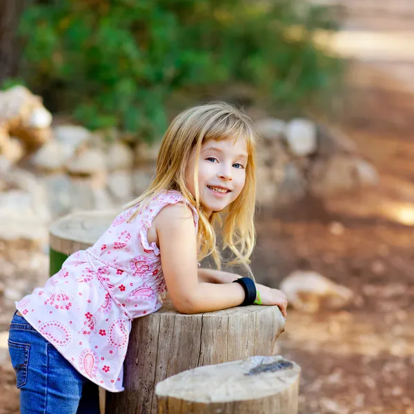 Ağaç gövde ormandaki sarışın çocuk kız — Stok fotoğraf
