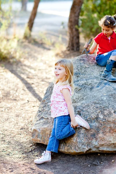 Vrienden kid meisjes spelen in bos rock — Stockfoto