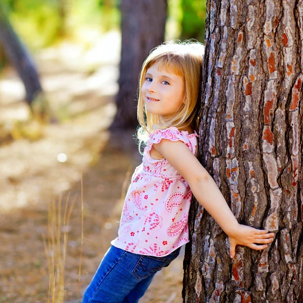 Blond kid girl on autumn tree trunk Stock Photo