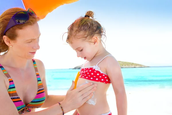 Figlia e madre in spiaggia con crema solare — Foto Stock