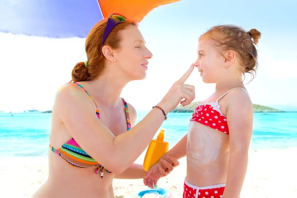 Figlia e madre in spiaggia con crema solare — Foto Stock