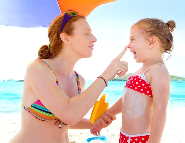Filha e mãe na praia com protetor solar — Fotografia de Stock