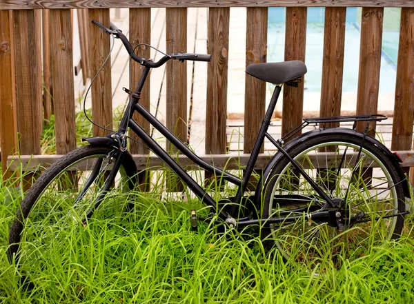 Bicicleta grunge preta envelhecida em uma cerca de madeira — Fotografia de Stock