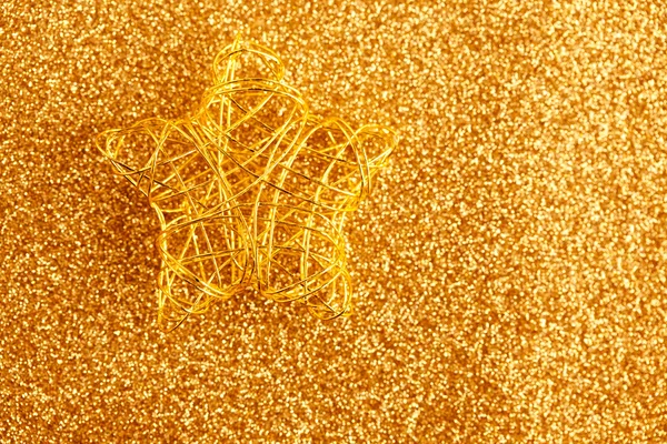 Christmas gold wire star on golden glitter — Stock Photo, Image