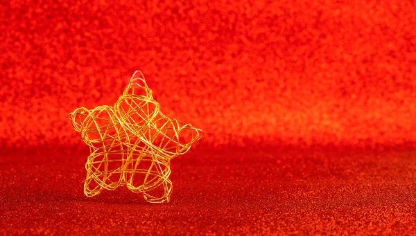 Christmas gold wire star on red glitter — Stock Photo, Image