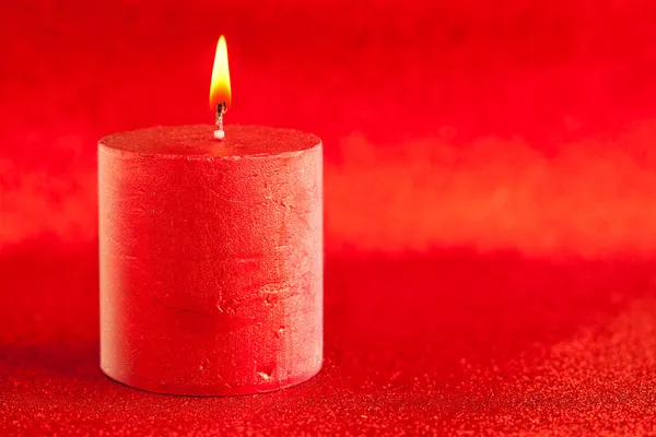 Christmas candle candlelight on red glitter — Stock Photo, Image