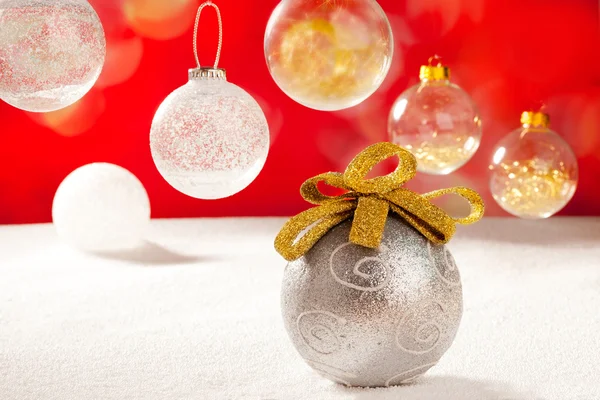 Рождественская серебряная безделушка с золотой петлей на снегу — стоковое фото