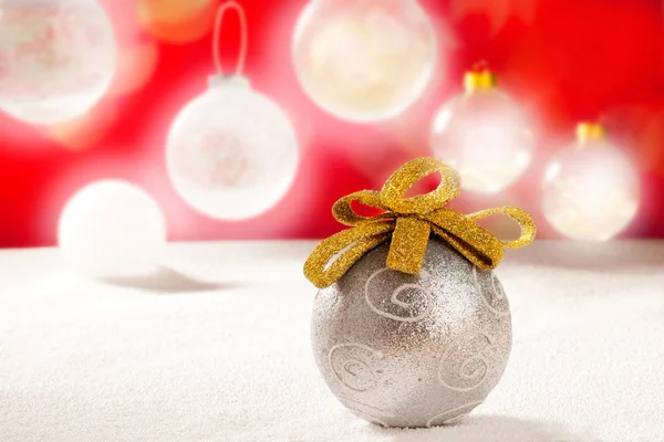 Bola de plata de Navidad con lazo de oro en la nieve —  Fotos de Stock