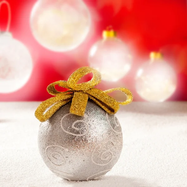 Рождественская серебряная безделушка с золотой петлей на снегу — стоковое фото
