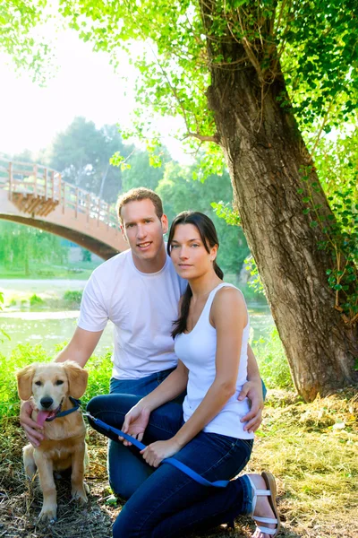 Par glada poserar med gyllene retirever hund — Stockfoto