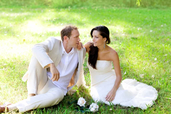 Pár právě oženil, sedí v parku trávy — Stock fotografie