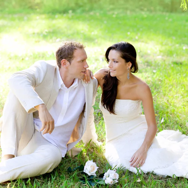 Casal acaba de se casar sentado na grama do parque — Fotografia de Stock