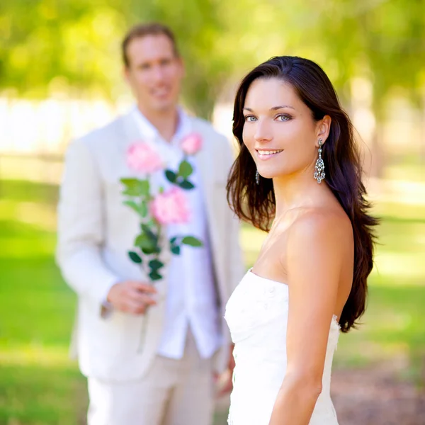 Casal recém-casado com homem segurando flores — Fotografia de Stock
