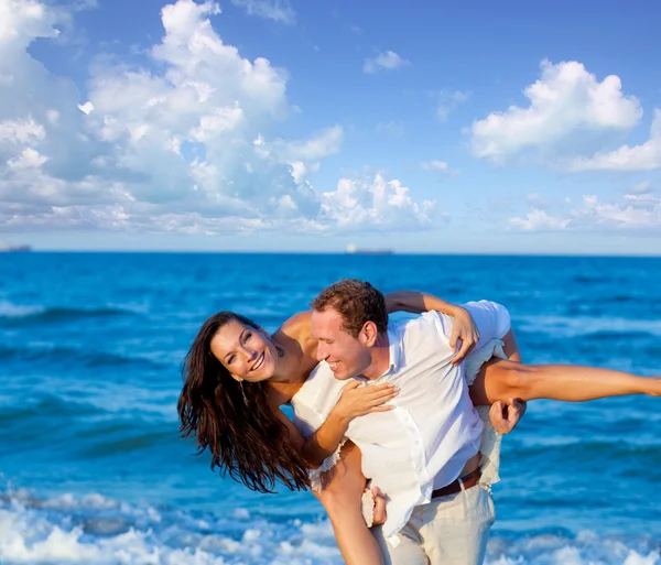 Couple in love piggyback playing in beach — Stock Photo, Image
