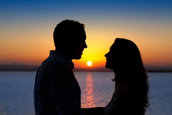 Pár v lásce podsvícení silueta na jezero západ slunce — Stock fotografie